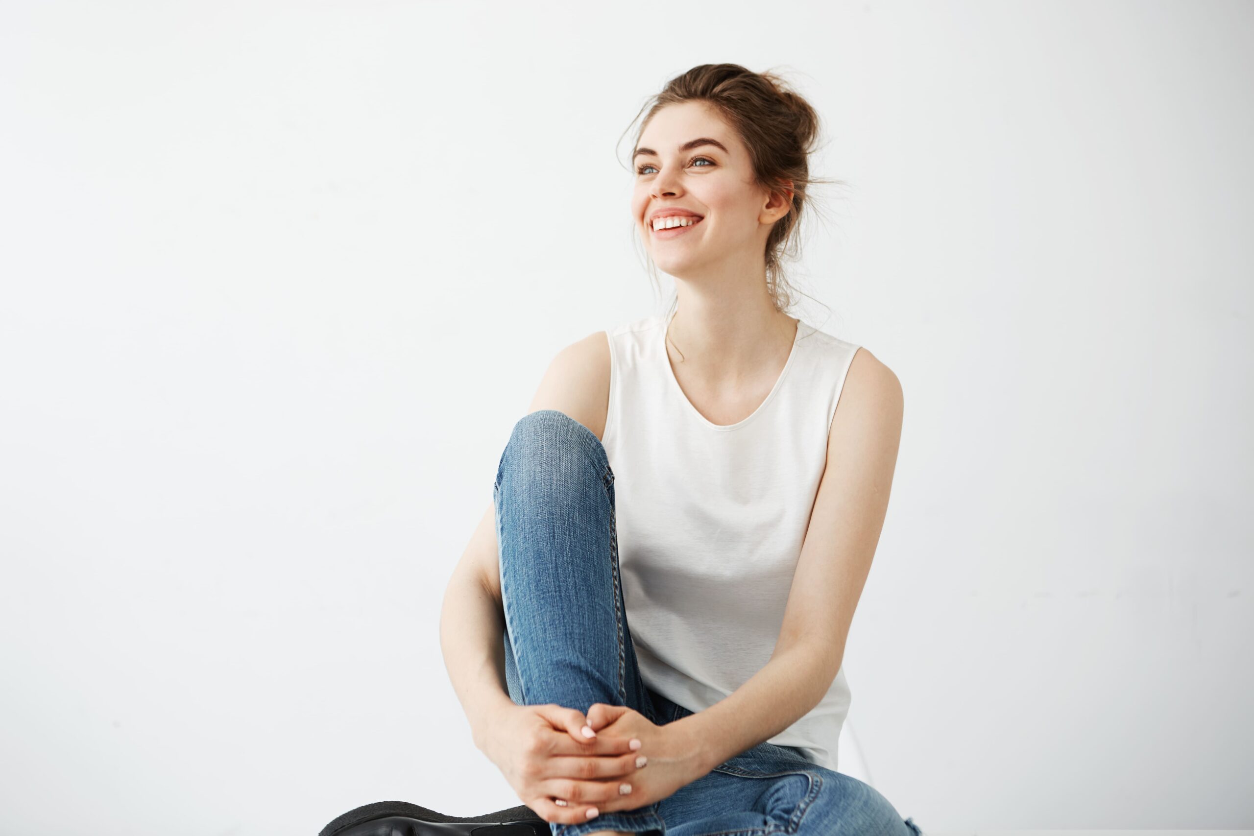 happy-young-beautiful-brunette-woman-with-bun-smiling-laughing-sitting-white-background (1)